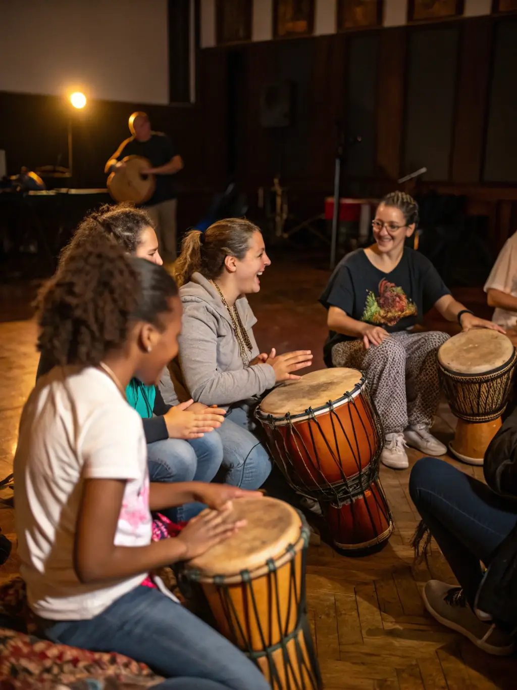 A diverse group of adults participating in a drumming workshop, with various percussion instruments visible, reflecting MUSIQUE JE T’AIME's inclusive approach to music education.